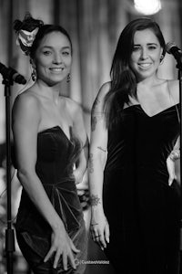 two women in black and white standing next to microphones