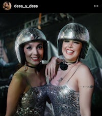 two women wearing disco helmets pose for a photo